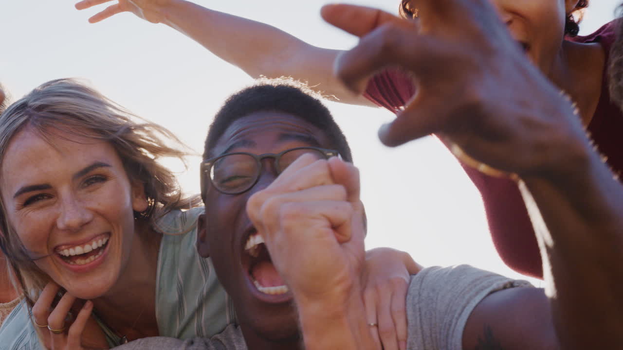 retrato de hombres dando a las mujeres mochilas como grupo de amigos sonriendo contra el sol ardiente