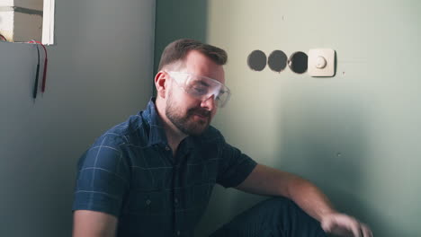 man-dances-sitting-near-switch-on-light-green-wall-in-room