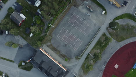 4k-Top-view-drone-shot-slowly-spinning-towards-the-tennis-court-outdoors-while-people-playing-together