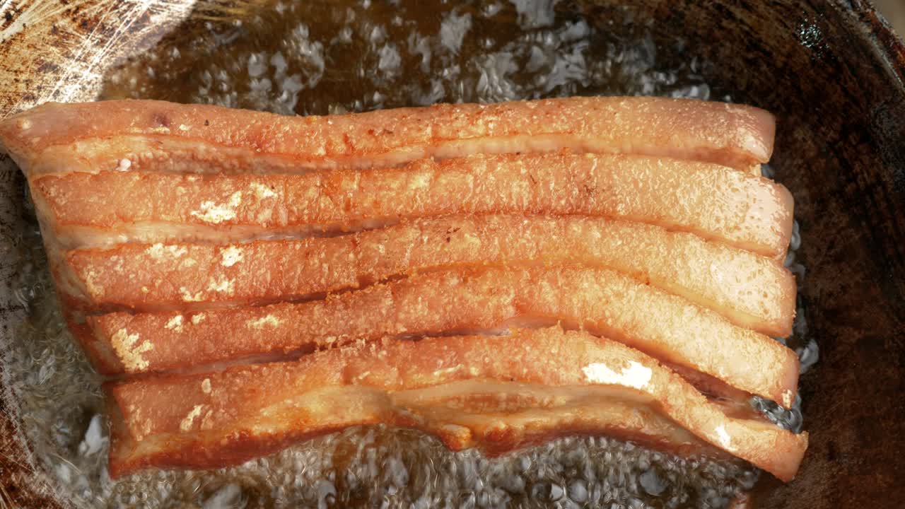 Pork belly deep frying in hot oil, top-down zoom in view