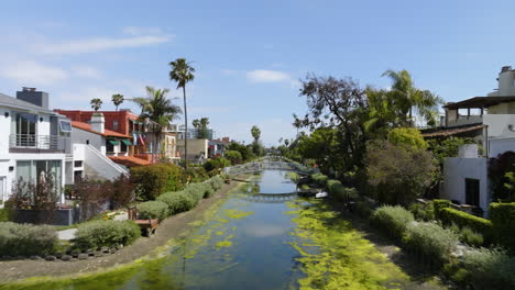 Aerial-view-low-over-the-still-Venice-canal-in-sunny-LA,-USA---reverse,-drone-shot