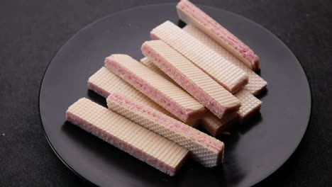 pink wafer cookies on a black plate