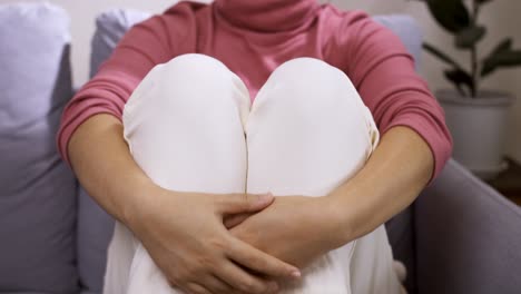 mujer joven nerviosa abrazando sus piernas, sintiéndose insegura