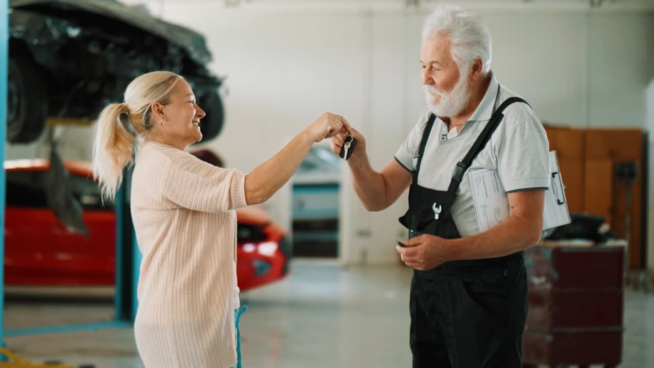 cliente femenina dando la llave del coche al mecánico de automóviles en el taller de reparación