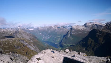 male hiker with a yellow jacket and red hat walking to the edge of mountain cliff to enjoy a stunning view