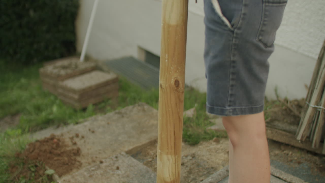 disparo medio de mano de una hembra golpeando un poste en la tierra