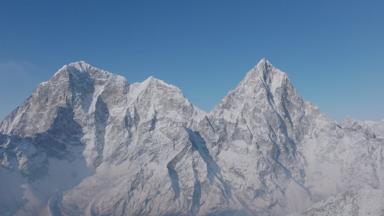 Drone view of Everest Base Camp trek in Khumbu, Nepal. Early morning sunrise reveals Khumbu Glacier and Cholatse Gokyo Peak under a clear blue sky, snowy ridges glowing in a heavenly Himalayan scene