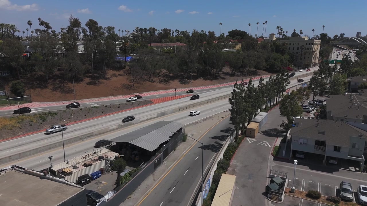 Autostrada a Los Angeles con auto in transito. Cielo azzurro limpido in una giornata di sole in California. Ripresa aerea 4K 60fps
