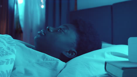 mujer afroamericana con insomnio acostada en la cama por la noche