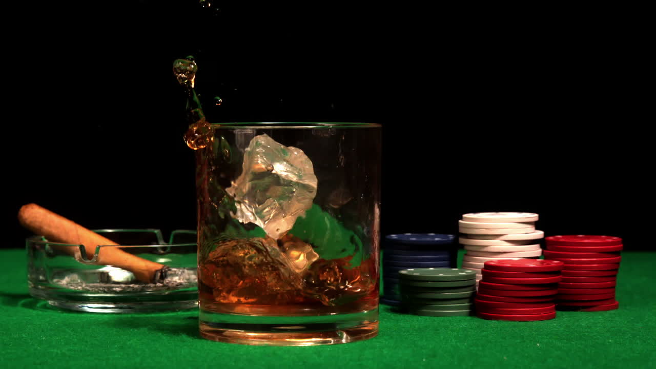 un cubo de hielo cayendo en un vaso de whisky en la mesa del casino