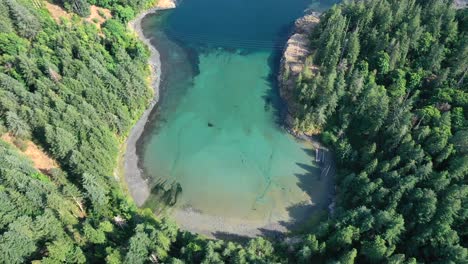 nature's horseshoe: overhead drone view of turquoise inlet surrounded by evergreens in campbell river