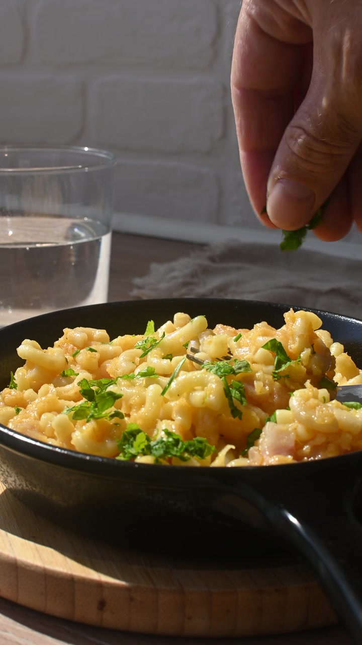 Cospargere prezzemolo fresco su maccheroni al formaggio cremosi fatti in casa