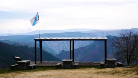 static establishing view of covered wooden pavillion with picnic bench tables at ribeira sacra canyon overlook