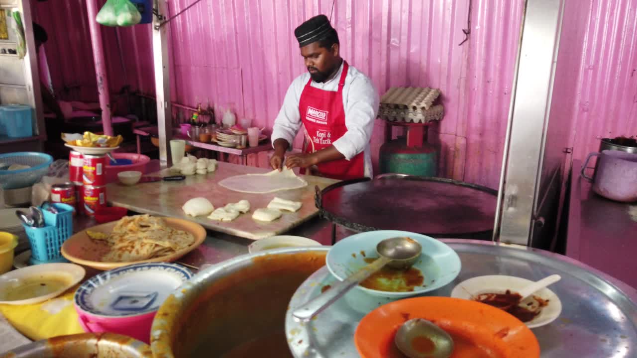 Indian man making roti canai (Indian-influenced flatbread dish), popular dish in southeast asia