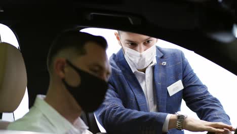 salesman presenting executive class car to a man inside of show room