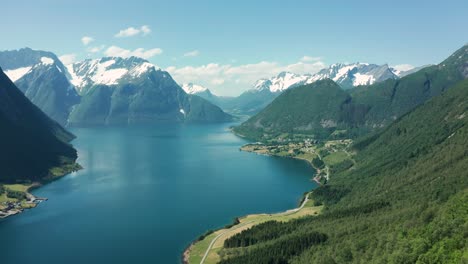 vista aérea de un profundo fiordo en noruega, rodeado de escarpados acantilados y montañas verdes bajo un cielo despejado