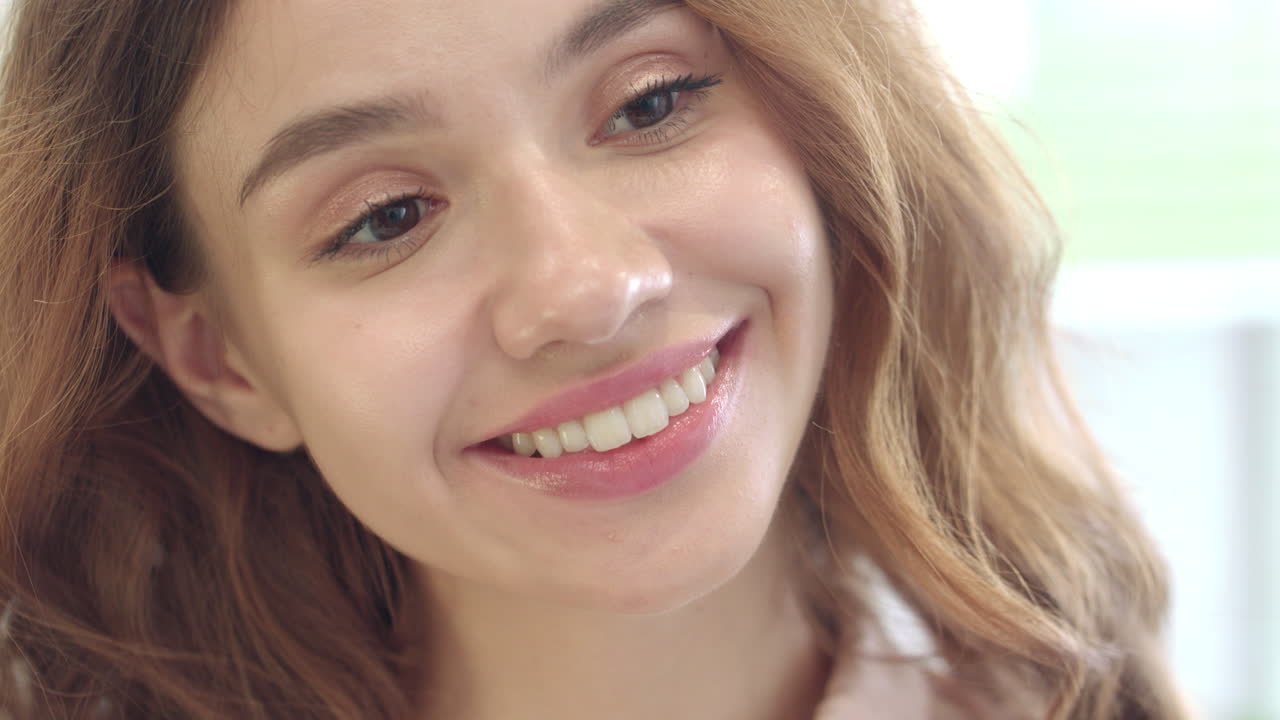 mujer alegre sonriendo y buscando frente al espejo en el baño de la casa