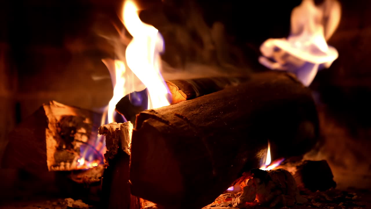 Firewood burning background. Fire flame and smoke on wooden logs in fireplace. Warmth and relaxation near the fireplace at winter season. Close-up.