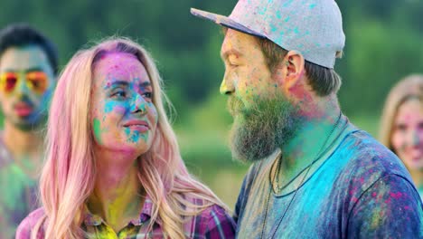 primer plano de la hermosa y alegre pareja divirtiéndose en el festival holi mientras está de pie al aire libre y sonriendo en polvo de pintura