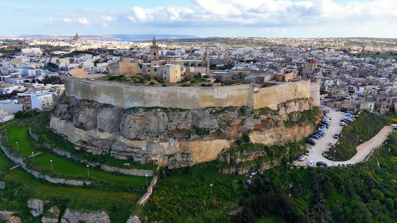 La Cittadella Il-Kastell a Victoria Rabat Gozo Malta si erge su una collina calcarea con bastioni fortificati e la Cattedrale dell'Assunzione rivelata sullo sfondo della campagna circostante, rivelazione con orbita di drone aereo.