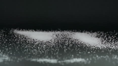 extreme slow motion and close up view of white salt grains moving up and down scattering around with acoustic vibration