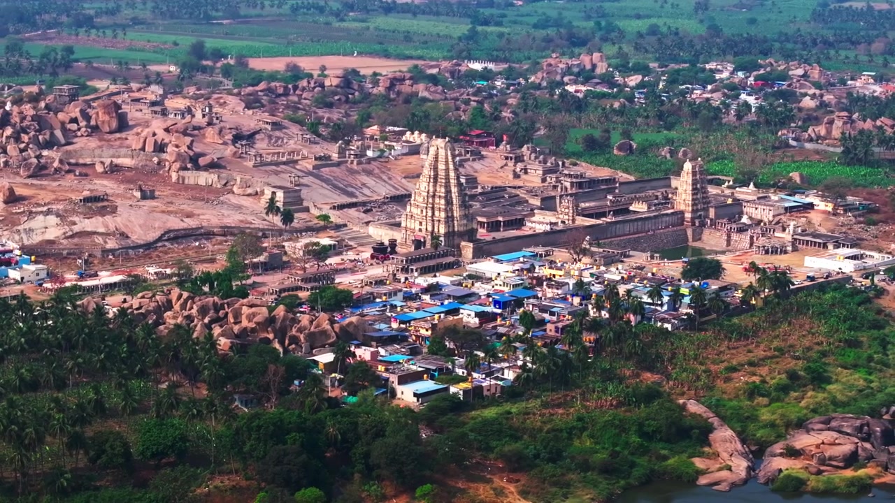 Veduta aerea del Tempio di Virupaksha con terreni agricoli, la Collina di Hemakuta, palme e fiume a Hampi, Vijayanagara, Karnataka, India. Di giorno, ripresa semi-orbitale con drone, 4K