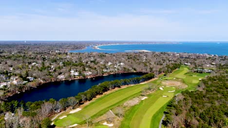 massive green and vibrant golf field near luxury town of osterville and atlantic ocean, aerial view