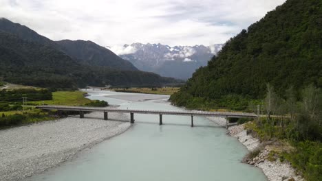 bridge over glacial river and high southern alps mountains in new zealand