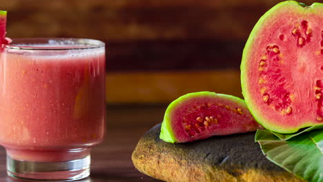 glass of red guava juice and sliced guava slice on wooden background