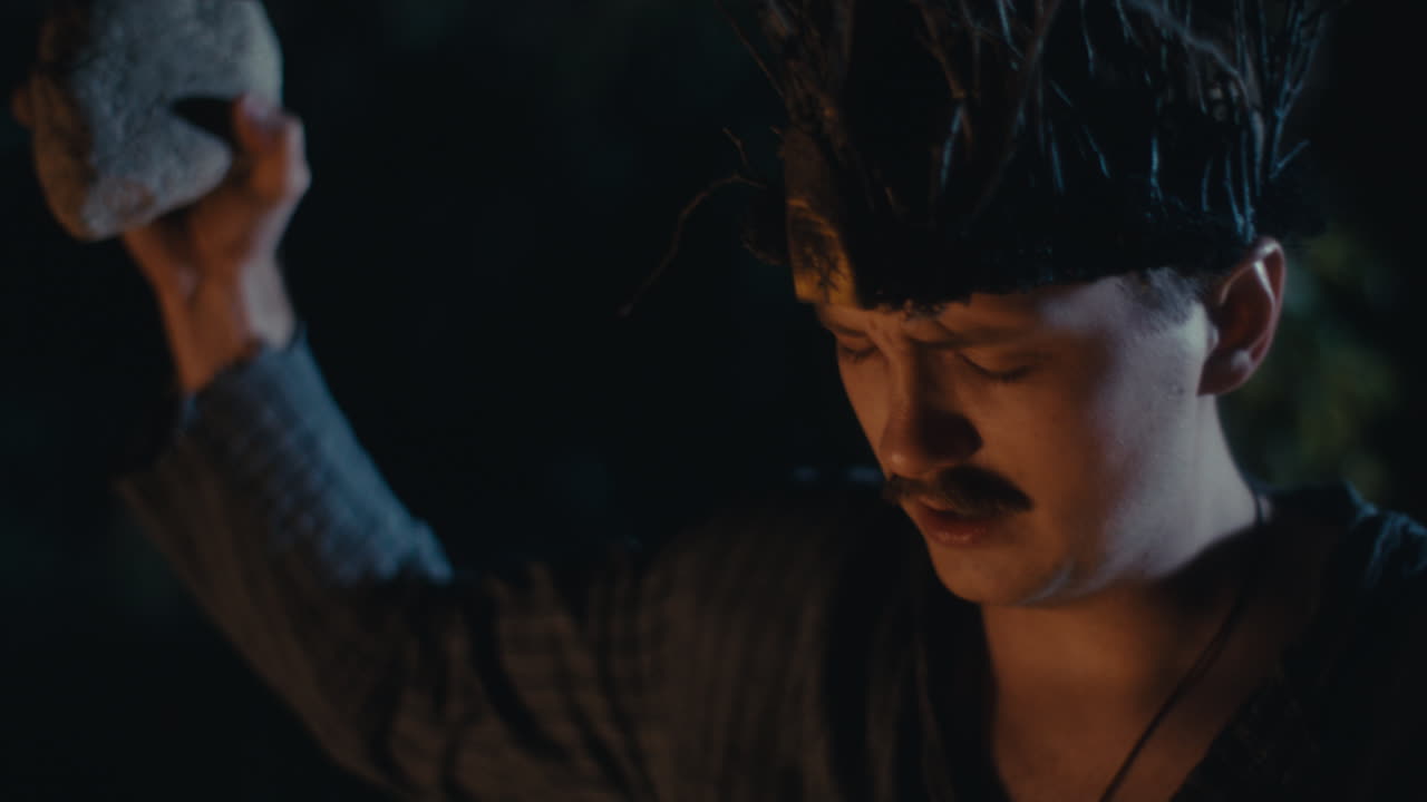 Man performing a night ritual with a rock
