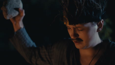 man performing a night ritual with a rock