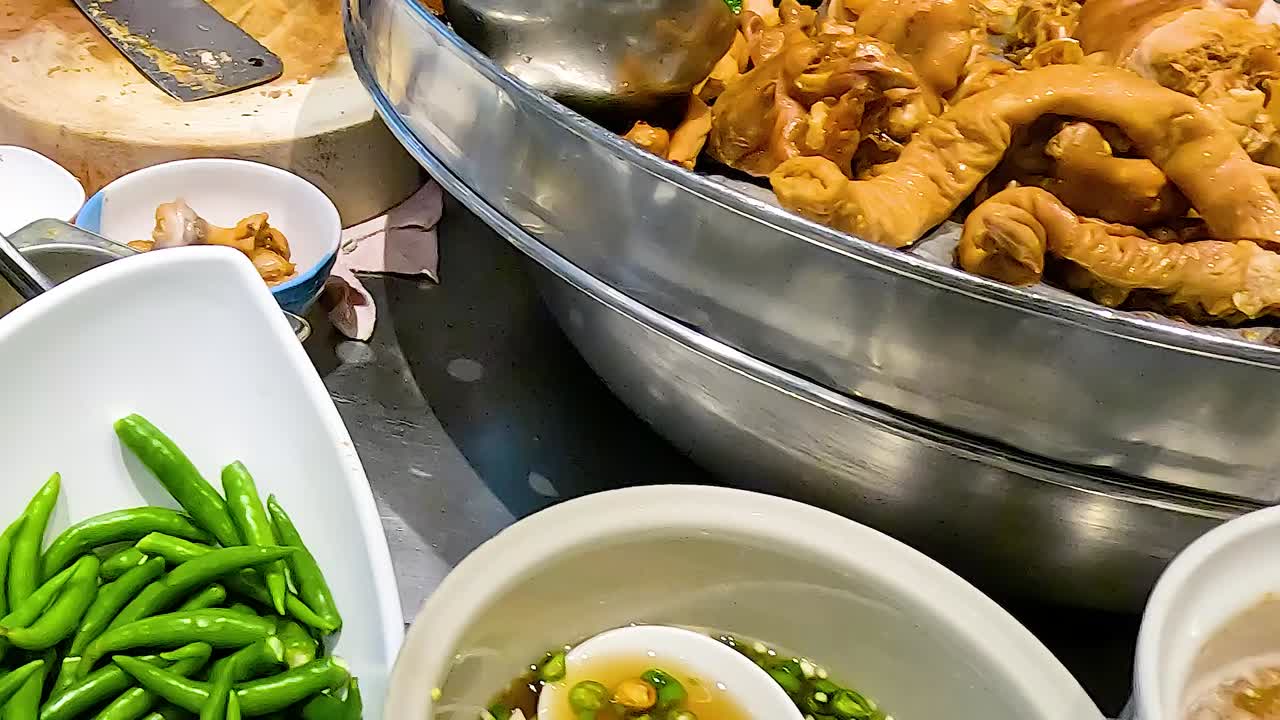 Close-up of stewed pork and green beans being prepared with sauce and garnishes.