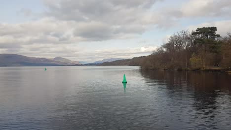 shot from a boat gliding across loch lomond in scotland’s trossachs national park on a cloudy winter day, capturing the moody beauty of the highlands