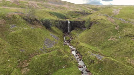 Force-gill-waterfall-between-bumpy-green-moorlands-near-Ribblehead-Viaduct,-Yorkshire,-aerial