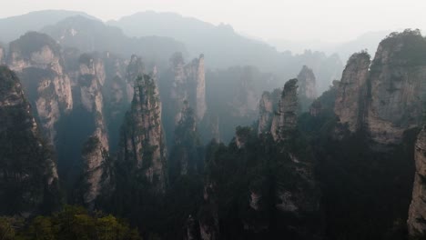 aerial view of forested sandstone towers stretching into the distance through soft morning haze in zhangjiajie national park