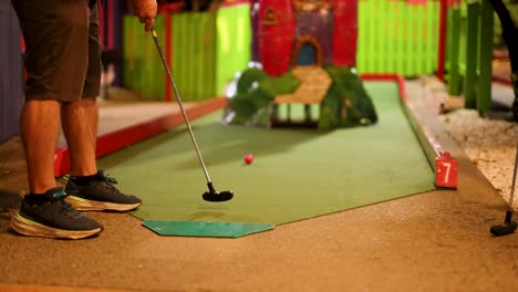 a person attempts a putt on a mini-golf course, humorously missing the hole. bright, colorful environment with playful atmosphere