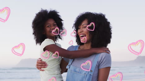 animation of happy african american mother and daughter embracing at beach over hearts