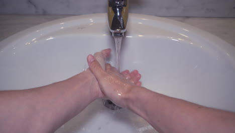 pov man washing male hand with soap and water under faucet