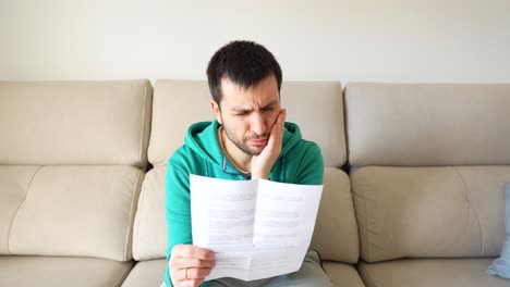 Medium-shot-of-white-man-reading-dental-instructions-holding-jaw-wincing-in-pain