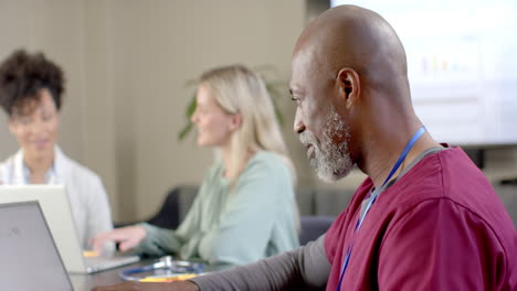 diverse doctors using laptops in meeting room with copy space, slow motion