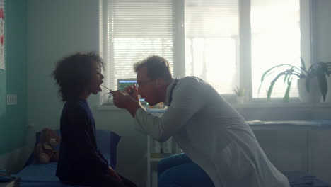 doctor examining girl throat in clinic. physician checking preteen child health.