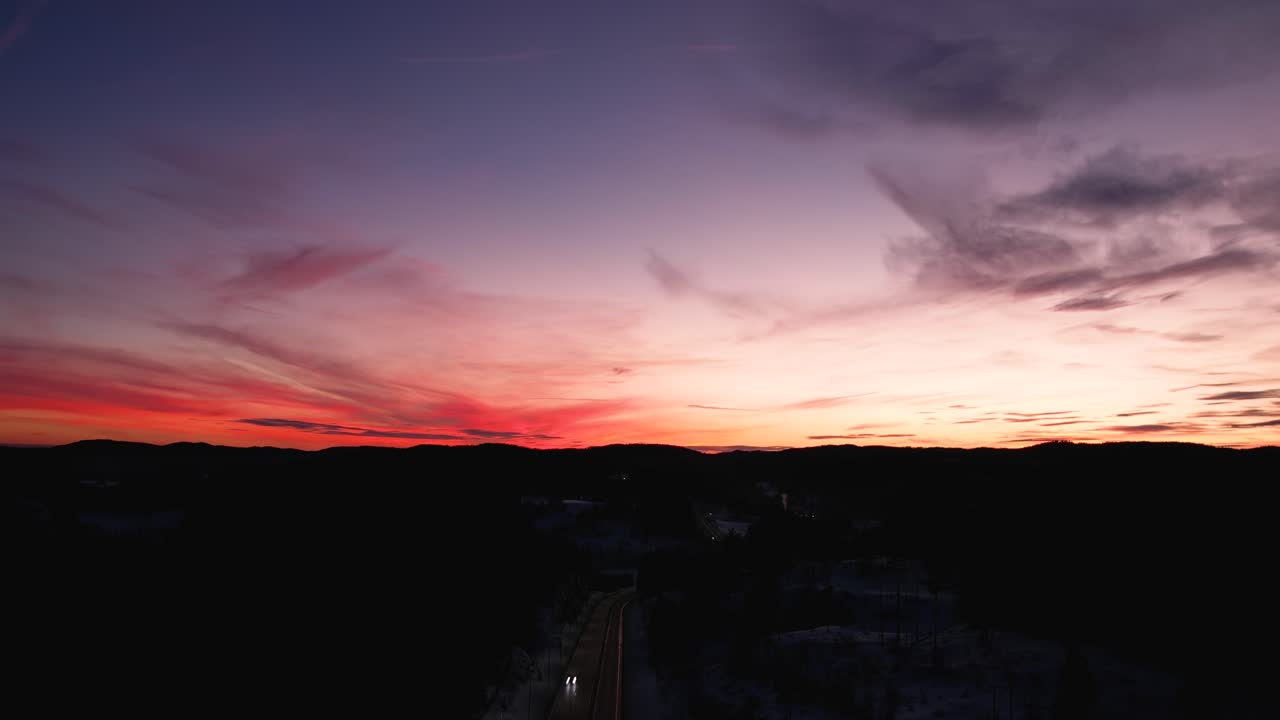 Volando sobre la autopista en las montañas de Noruega durante el atardecer