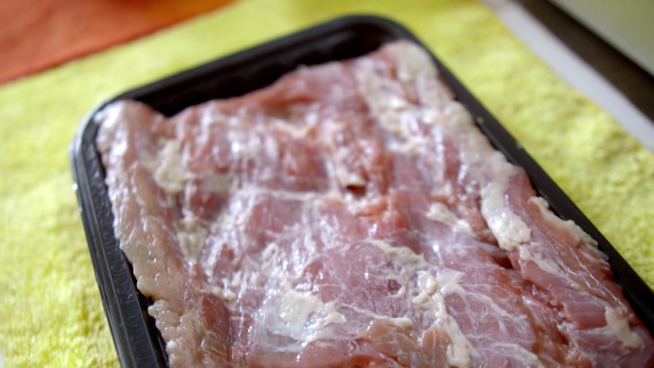 Raw meat in tray on colorful surface, culinary preparation, fresh food