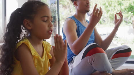 padre y hija bi-raciales felices haciendo yoga, meditando juntos