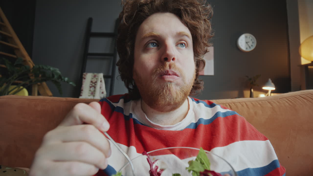 Man eating salad on a couch