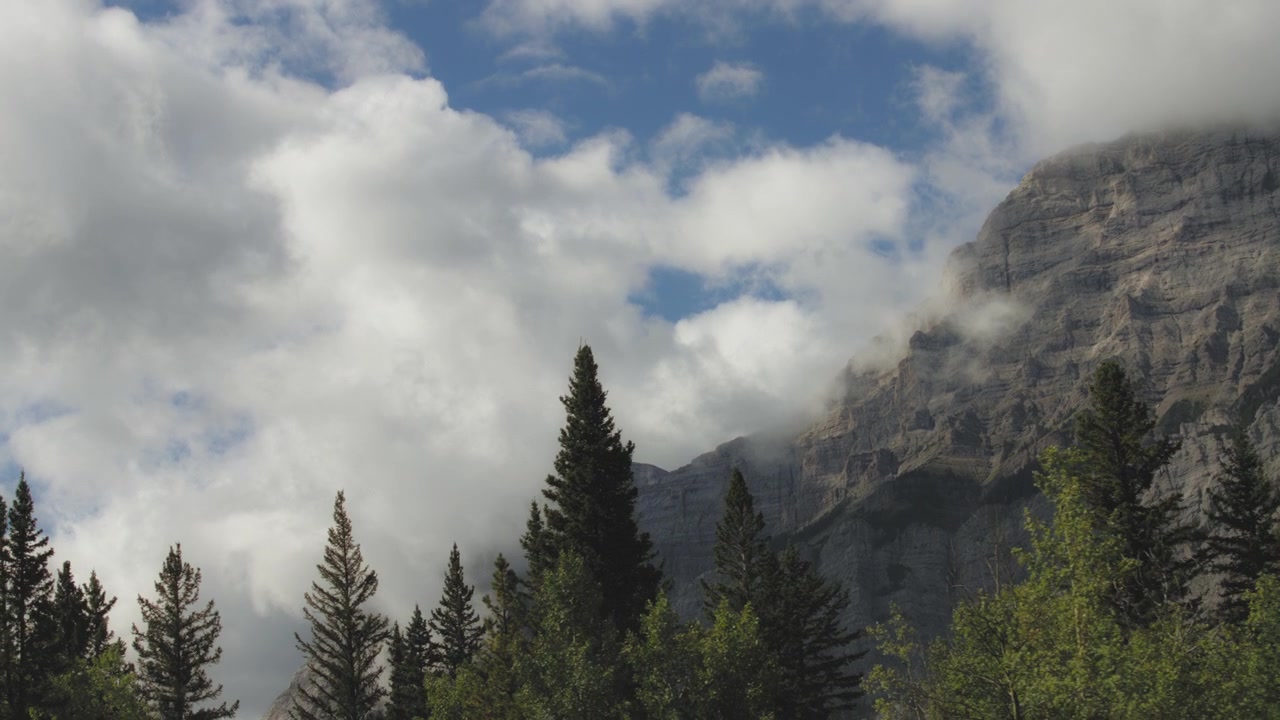 Passando accanto a pini e alte vette delle Montagne Rocciose coperte di nuvole