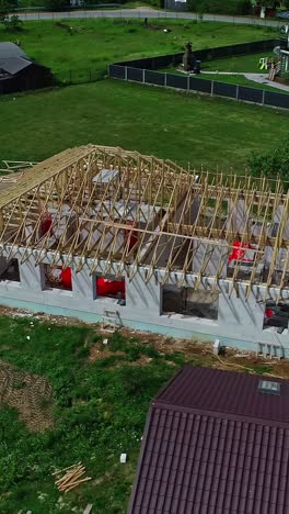 wooden roof framing and trusses of a new residential house being built in the latvian countryside, showing the home construction process - aerial vertical parallax