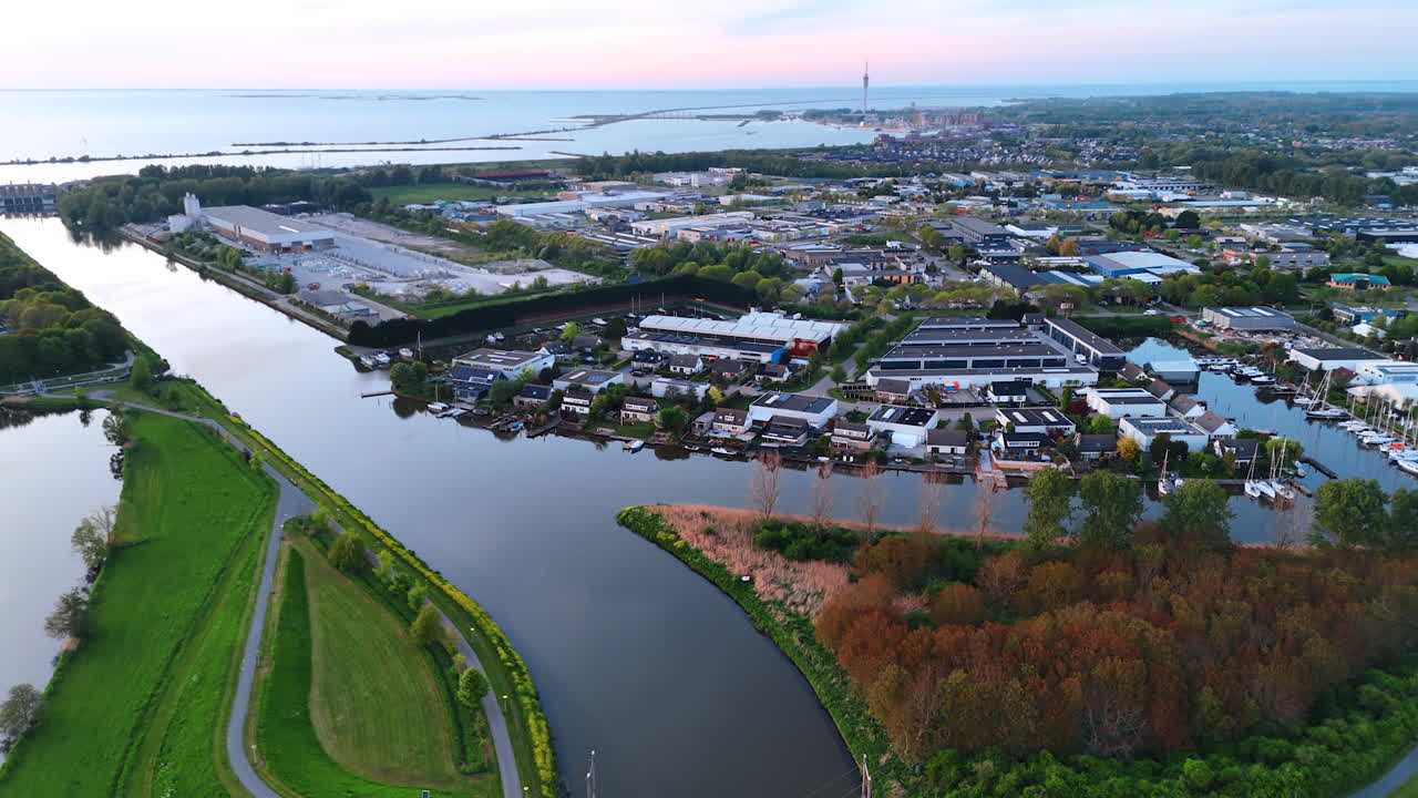 Footage over the bridge connecting the banks of the canal. Revealing view on the lovely country in the Netherlands at sunset time.