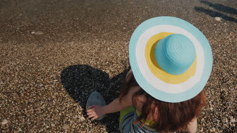 una joven con el pelo largo y oscuro con un sombrero textil de colores brillantes se sienta en la vista de la costa desde el