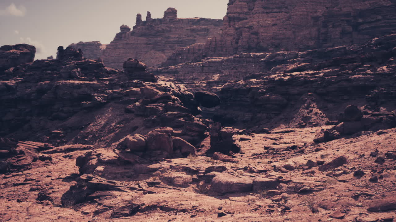 Boulders and sunlit sandstone layers with scattered smaller stones present